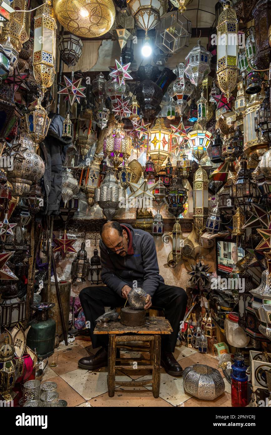Artigiano che fa lampade in metallo in un negozio nella medina di Marrakech. Foto Stock