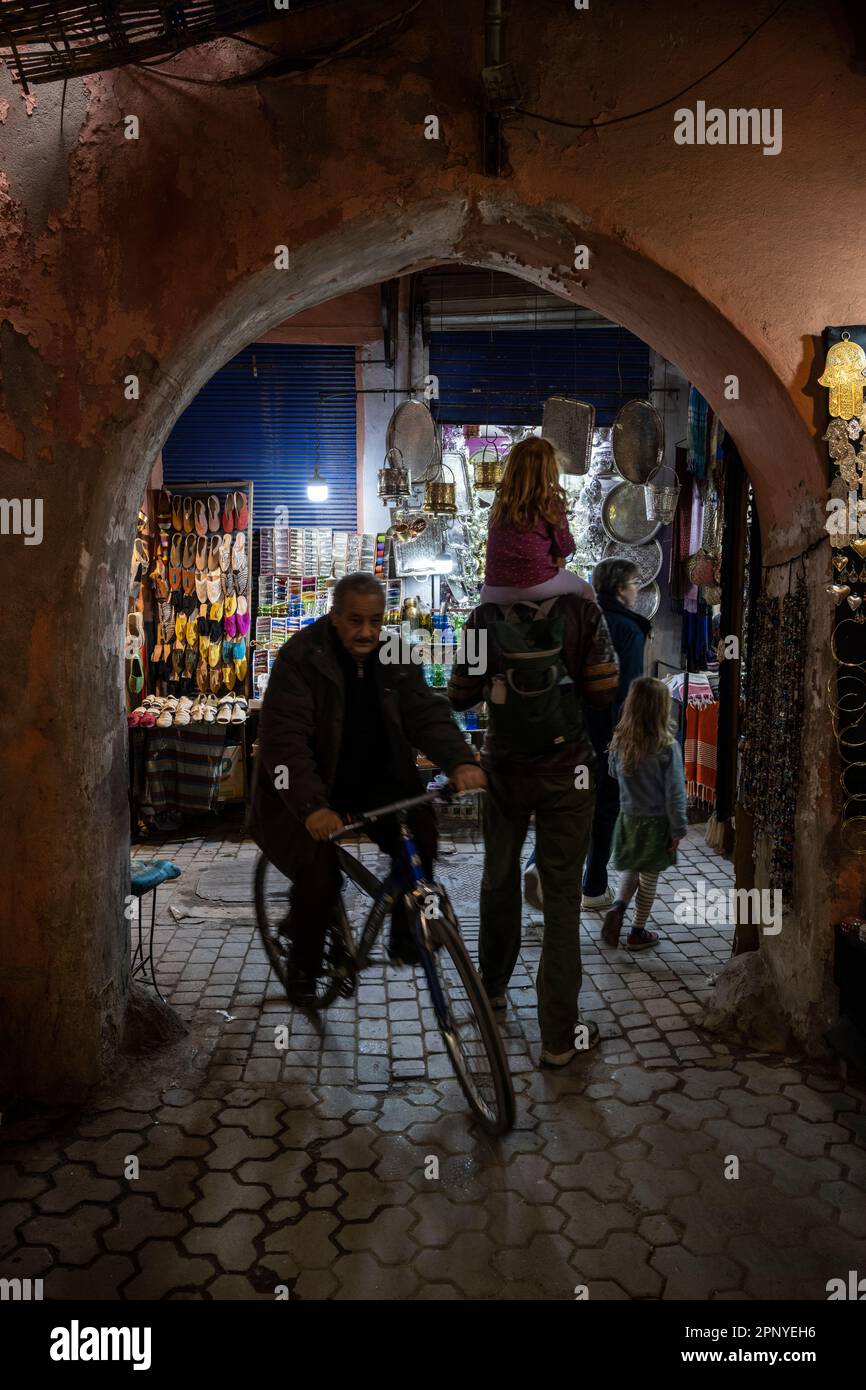 Gente nelle strade della medina di Marrakech con i tipici negozi di souvenir. Foto Stock