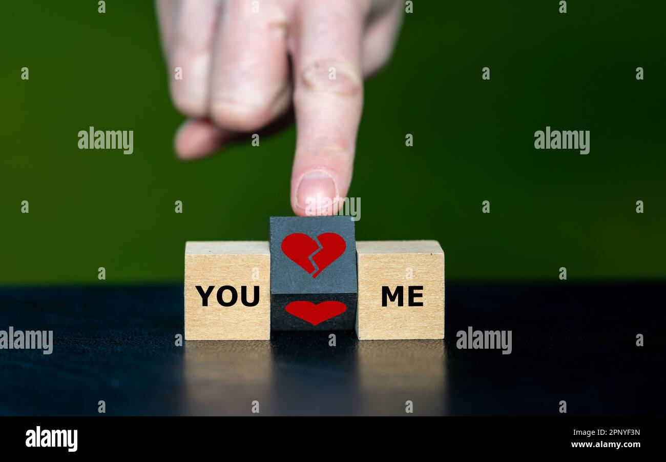 Simbolo per la rottura di una relazione. La mano gira il cubo di legno e cambia il simbolo di un cuore in un simbolo di un cuore spezzato. Foto Stock