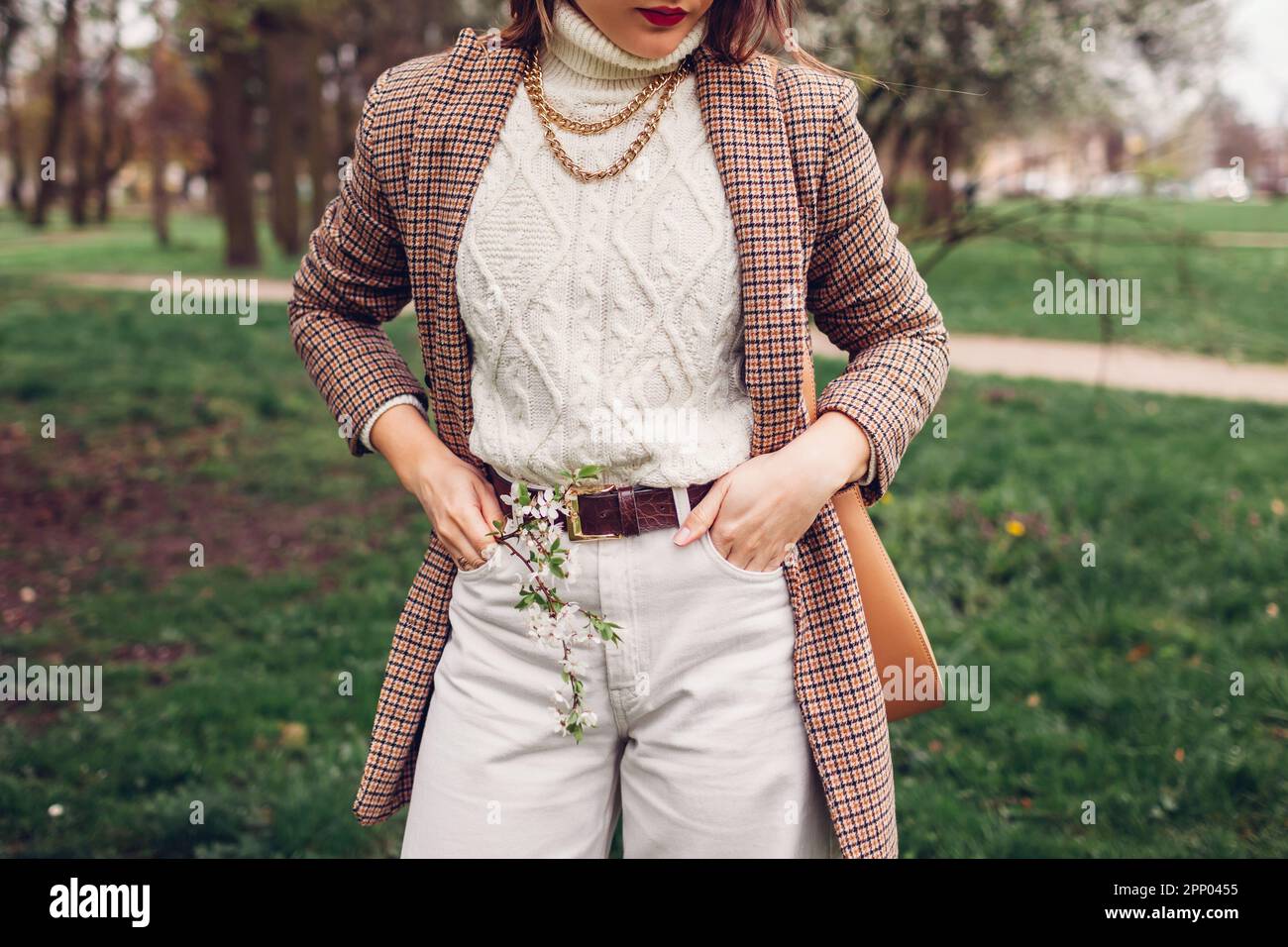 Primo piano all'aperto di una giovane donna che indossa un maglione bianco e pantaloni con borsa marrone blazer. Accessori e abbigliamento in stile retrò. Female Foto Stock