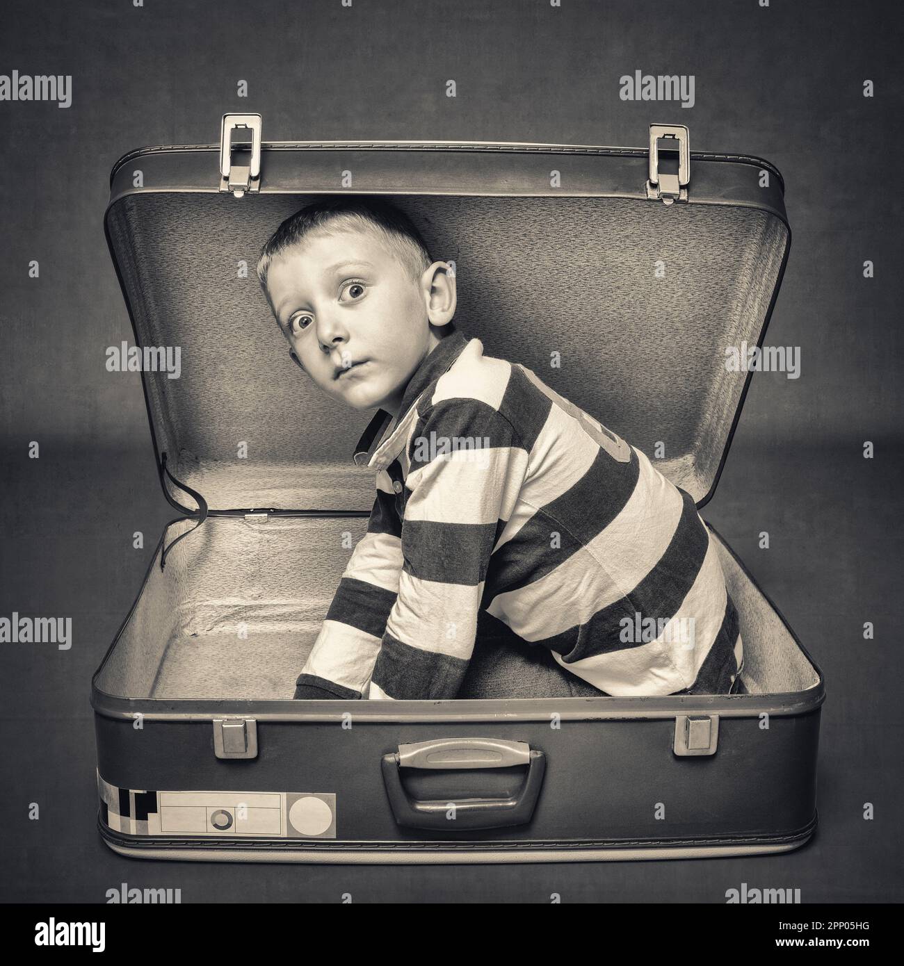 bambino con espressione stupefacente in una valigia vintage Foto Stock