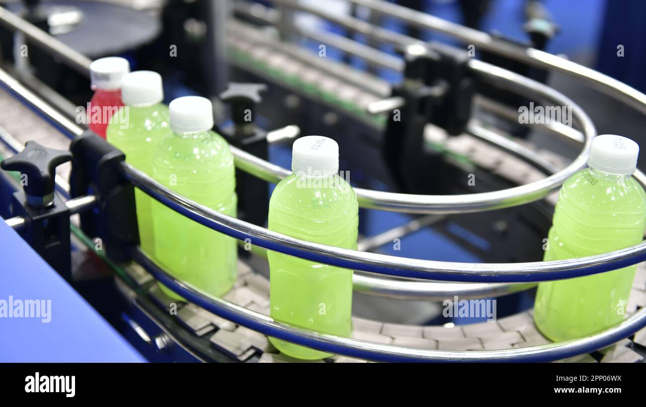 Le bottiglie di succo in plastica trasferiscono su sistemi trasportatori automatizzati automazione industriale per le confezioni Foto Stock