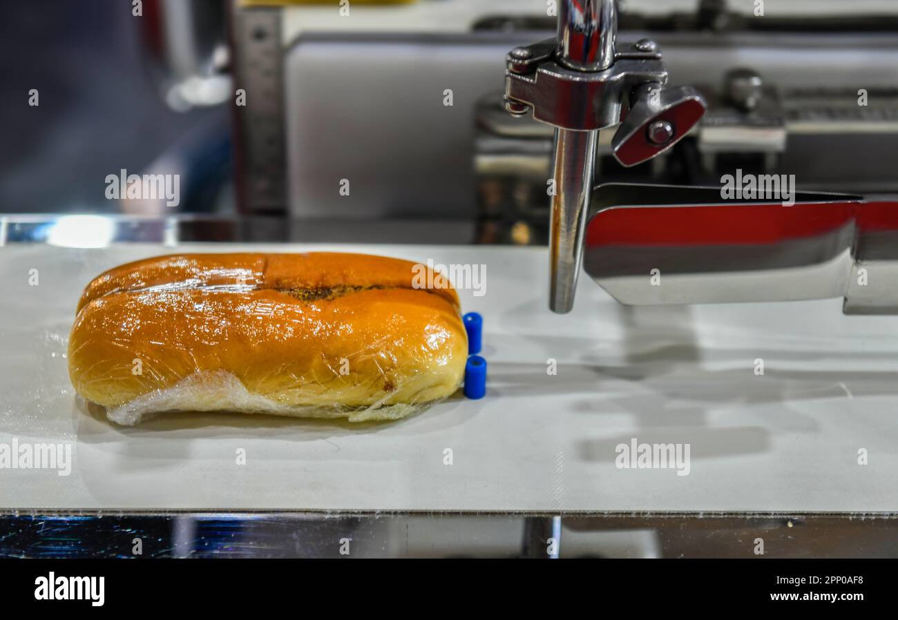 Linea di produzione automatica di panini per hamburger su macchine per nastri trasportatori in fabbrica, produzione alimentare industriale. Foto Stock