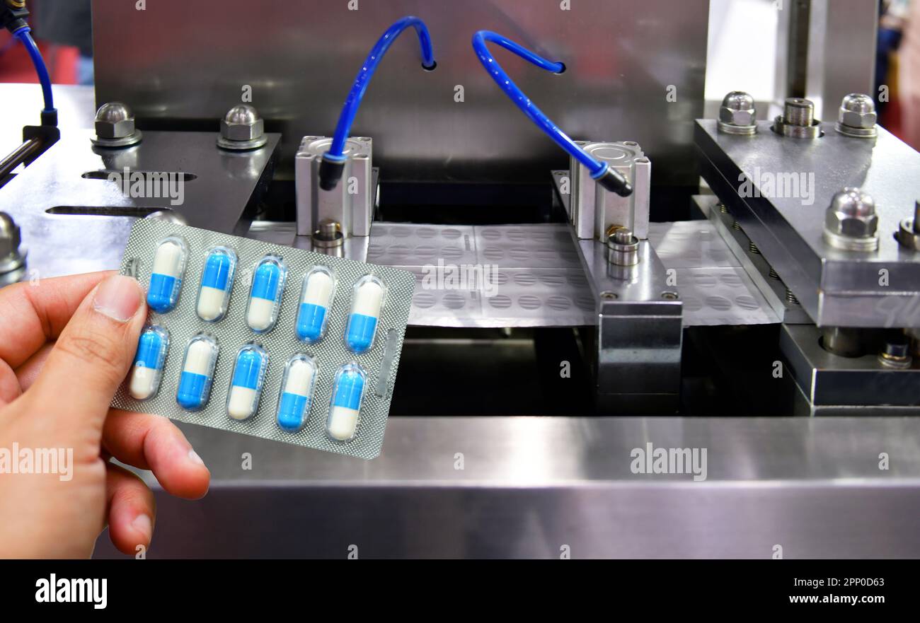 Confezione di capsule blu per la conservazione delle mani presso la linea di produzione di pillole mediche, concetto farmaceutico industriale. Foto Stock
