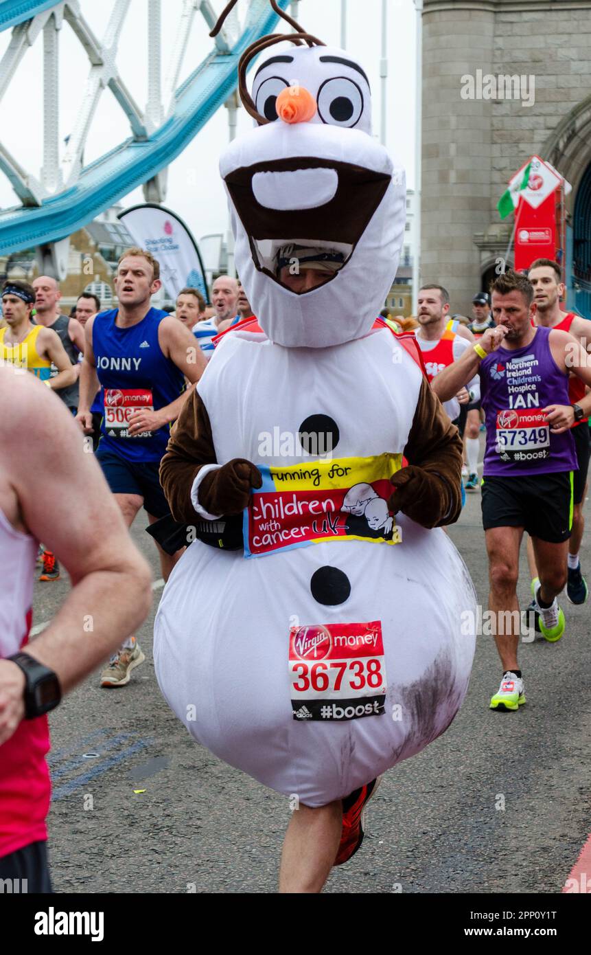 Corridore in costume OLAF costume abito fantasia in gara nella Virgin Money London Marathon 2015 attraversando Tower Bridge, Regno Unito. Correre per beneficenza Foto Stock