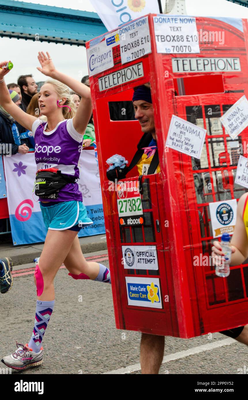 Corridore nella scatola telefonica costume di abito di fantasia in competizione nella Virgin Money London Marathon 2015 attraversando Tower Bridge, Regno Unito. Tentativo di registrazione ufficiale Foto Stock
