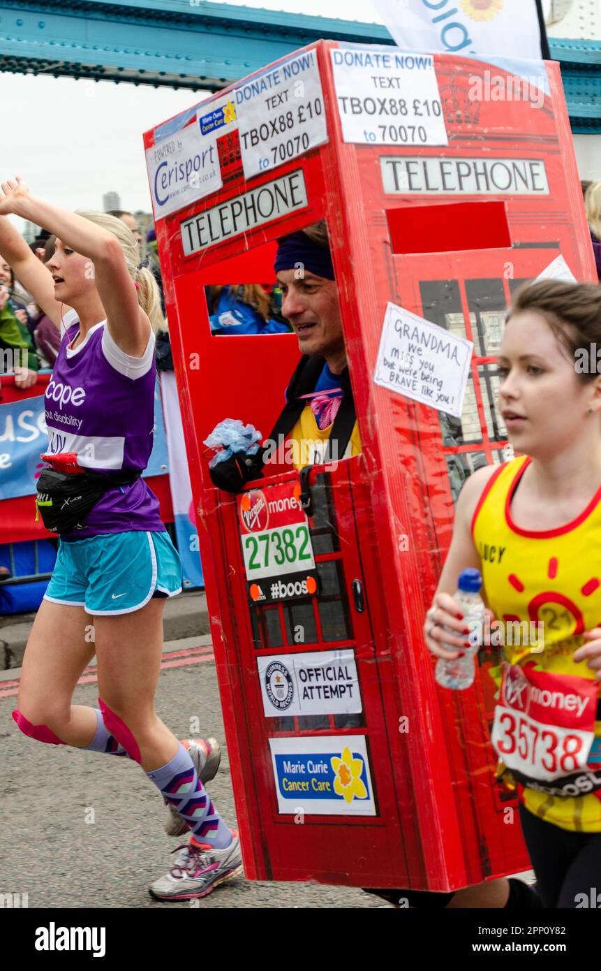 Corridore nella scatola telefonica costume di abito di fantasia in competizione nella Virgin Money London Marathon 2015 attraversando Tower Bridge, Regno Unito. Tentativo di registrazione ufficiale Foto Stock