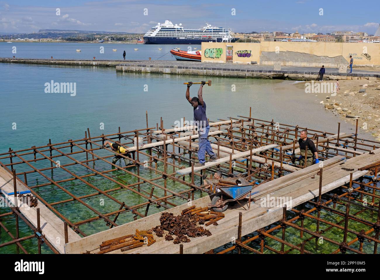 Costruire, costruire, erigere ponteggi in mare, spiaggia, per costruire una piattaforma per la spiaggia cittadina di Siracusa. Foto Stock