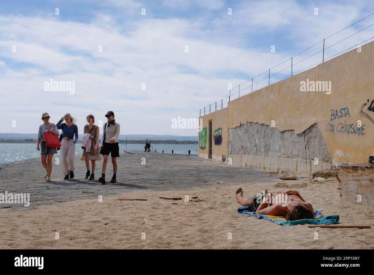 Turisti a piedi sulla spiaggia cittadina di Siracusa, in Sicilia. Foto Stock