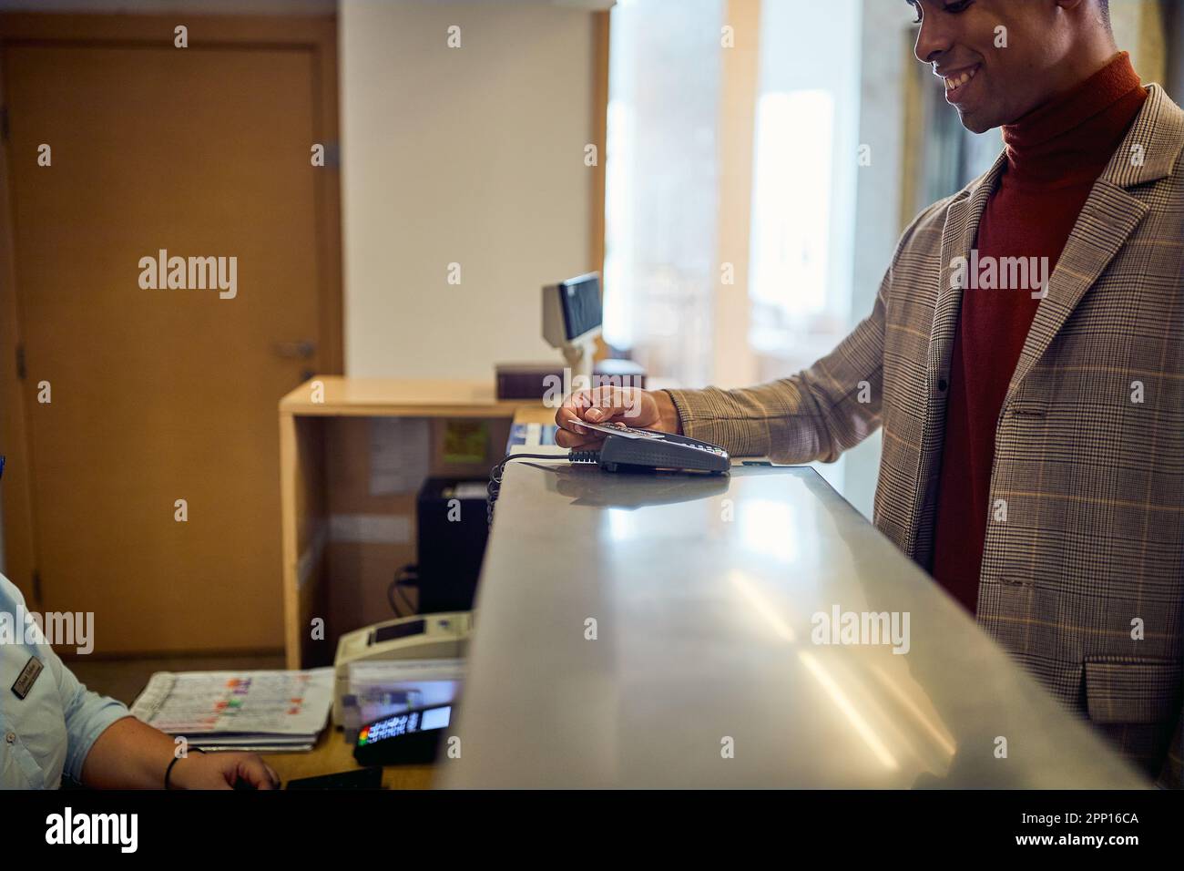 Un giovane uomo d'affari di buon umore sta effettuando il check-in in un hotel durante un viaggio d'affari. Affari, persone, hotel, viaggio Foto Stock