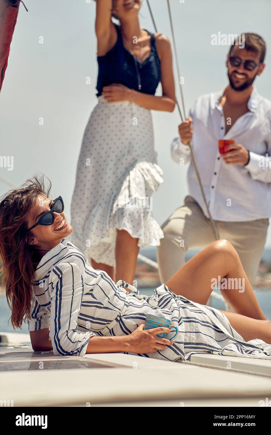 Una giovane bella modella femminile si sta posando per una foto mentre si passa un tempo meraviglioso con i suoi amici a una foto di ripresa su uno yacht su una bella somma Foto Stock