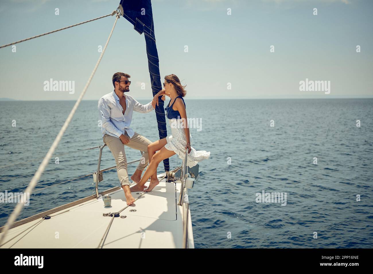 Una giovane coppia sta chiacchierando sulla prua dello yacht mentre gode di una vista e di un giro in una bella giornata di sole sul mare. Estate, mare, vacanza, relati Foto Stock