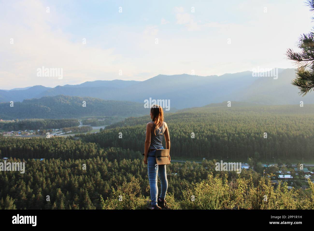 Concept donna viaggiatore in un viaggio da solo, in piedi su una collina, guardando in lontananza. Foto d'estate al tramonto, foresta verde con clima caldo. Natura Foto Stock