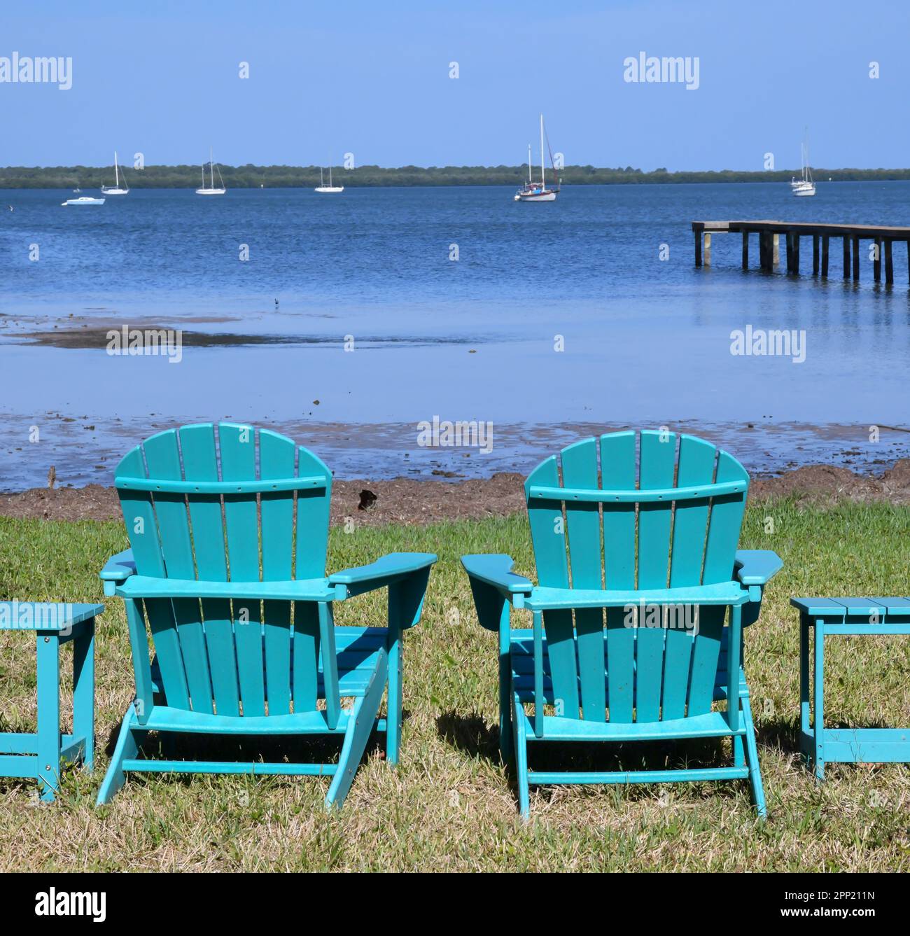 Sedie a prato Adirondack vuote lungo la riva dell'oceano Foto Stock