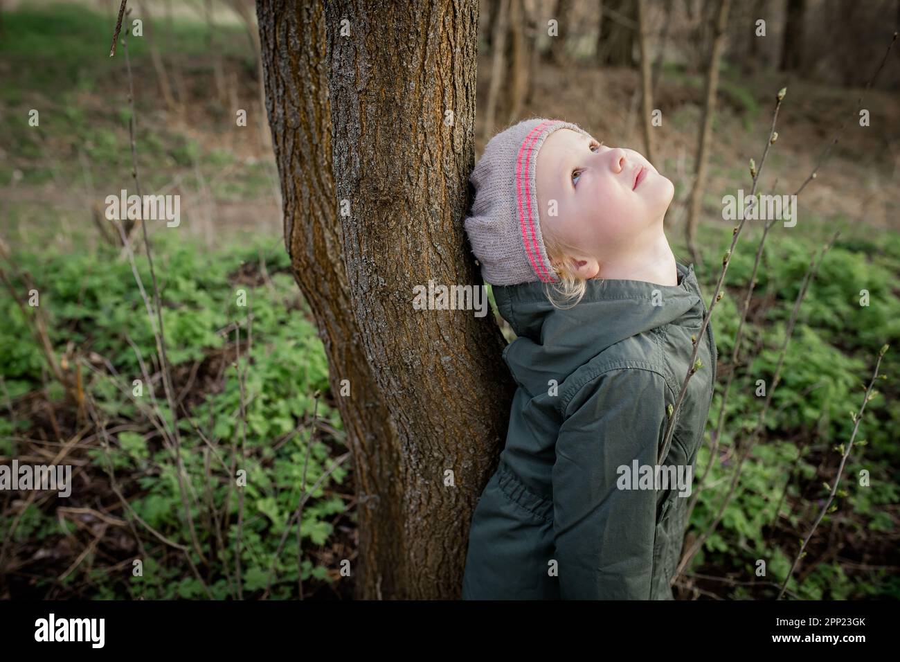 Pratica di bambina . la ragazza si appoggiò all'albero con la schiena e guardò in alto, godendo dell'energia della natura. Terapia dell'albero Foto Stock