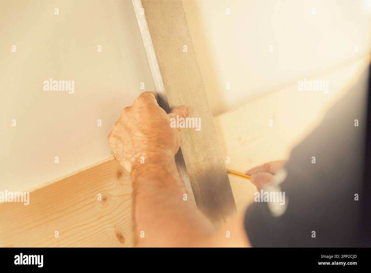 Un artigiano del legno traccia le linee e le misure nel suo negozio di legno luminoso. Egli è concentrato e competente, la sua esperienza è tutto personale e. Foto Stock