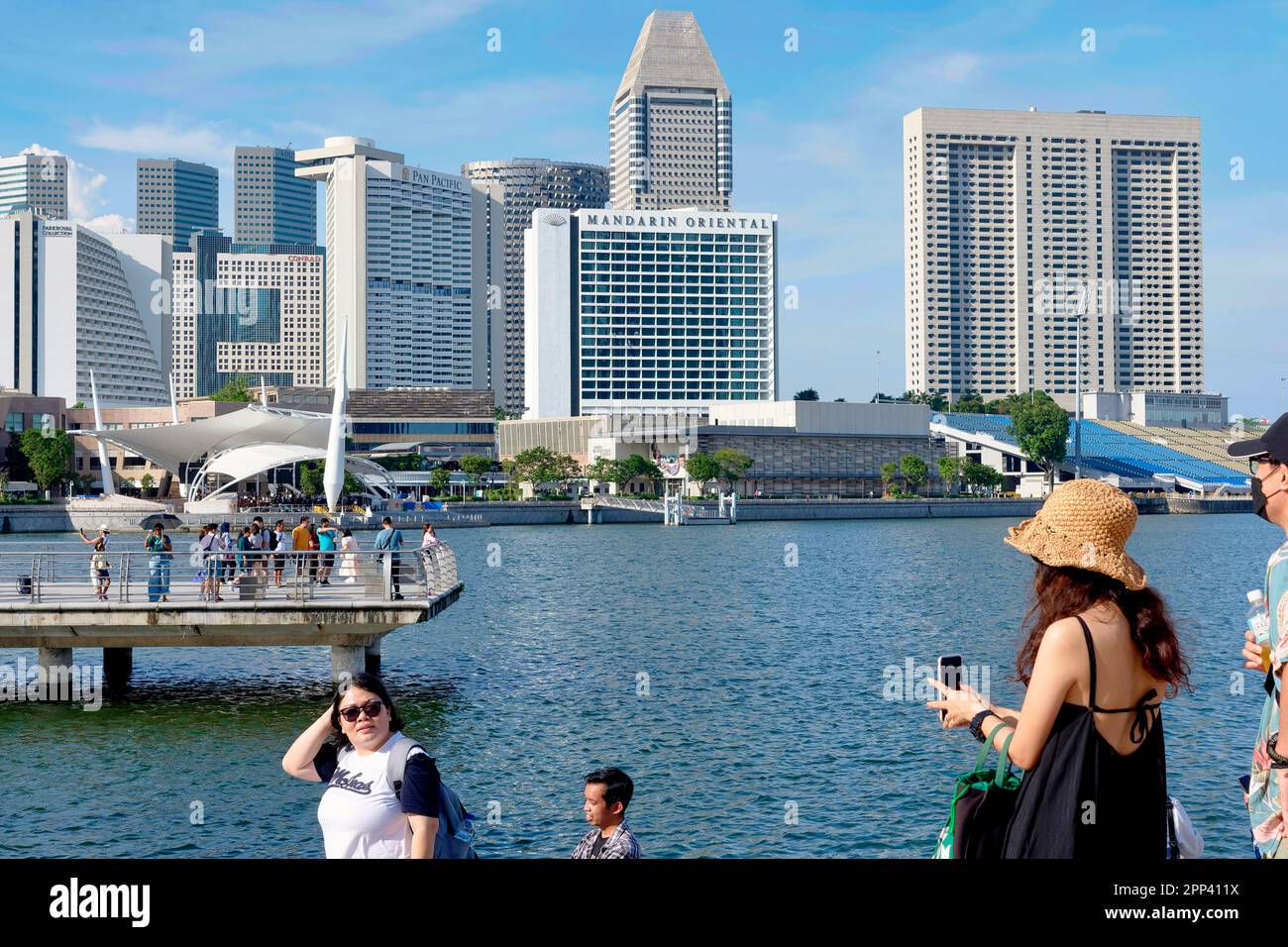 I turisti dell'Asia orientale godono della vista di Marina Bay, Singapore, con i vari hotel di lusso e altri alti edifici sullo sfondo Foto Stock
