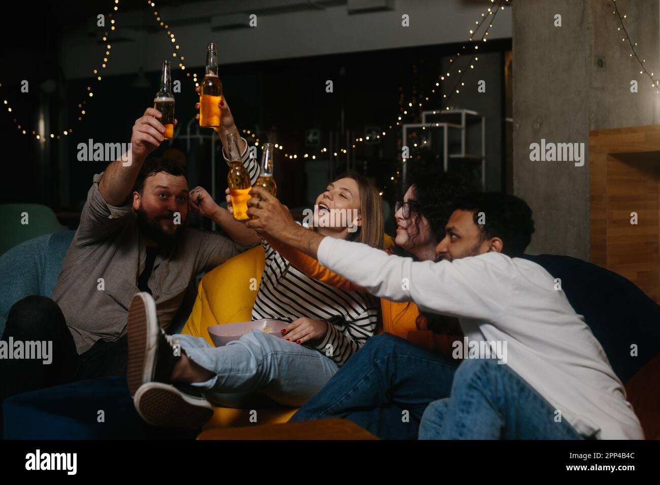 Un gruppo di amici si divertono insieme in un bar la sera, bevono birra e chiacchierano. Foto Stock