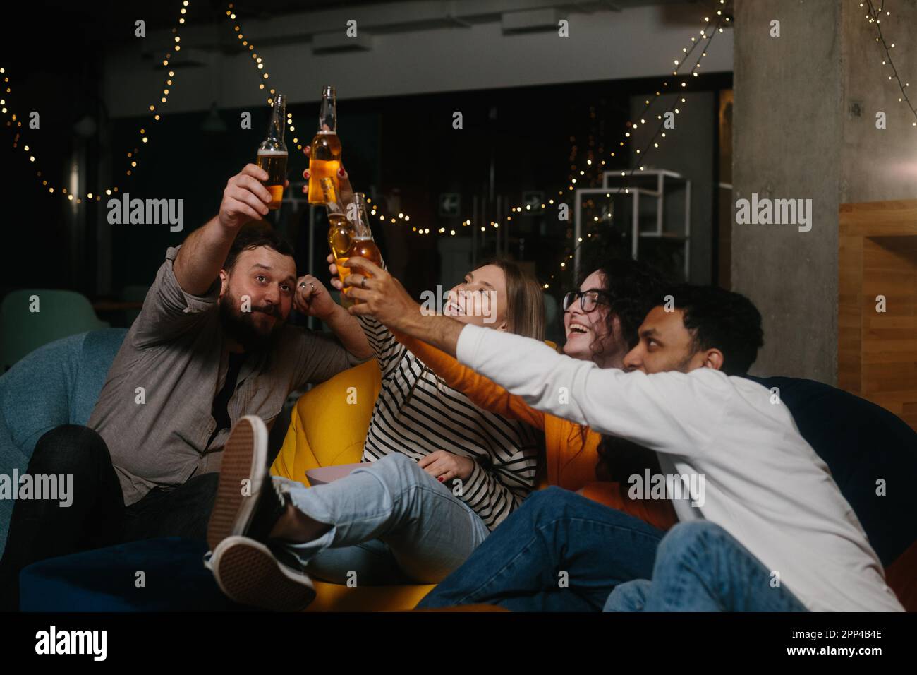 Un gruppo di amici si divertono insieme in un bar la sera, bevono birra e chiacchierano. Foto Stock