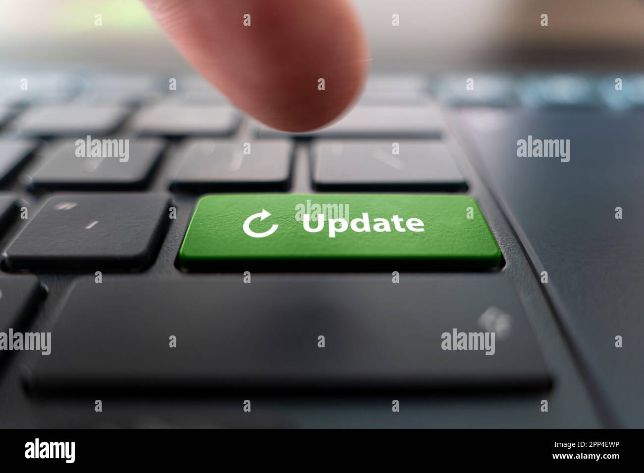 Uomo che preme il tasto verde con AGGIORNAMENTO parola sulla moderna tastiera nera del computer, primo piano Foto Stock