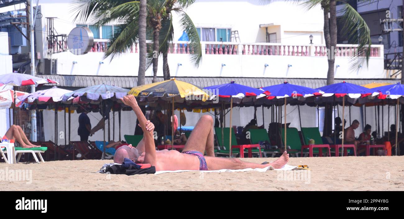 Un uomo che indossa un costume da bagno si trova sulla spiaggia prendendo il sole a Pattaya, Thailandia, Asia. Foto Stock