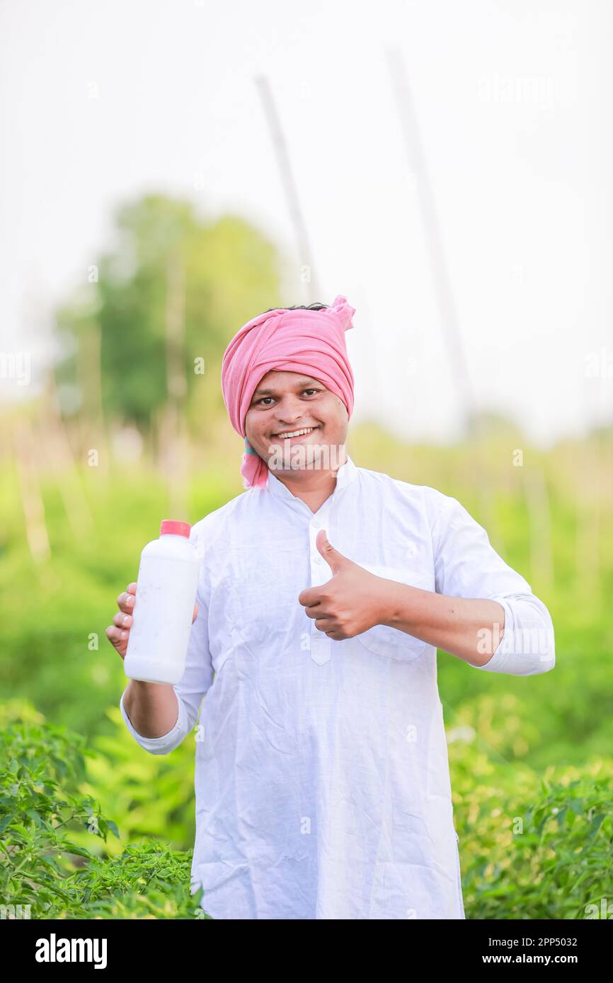 Giovane agricoltore indiano che mostra smartphone, agricoltore che parla al telefono in fattoria, agricoltore indiano felice Foto Stock