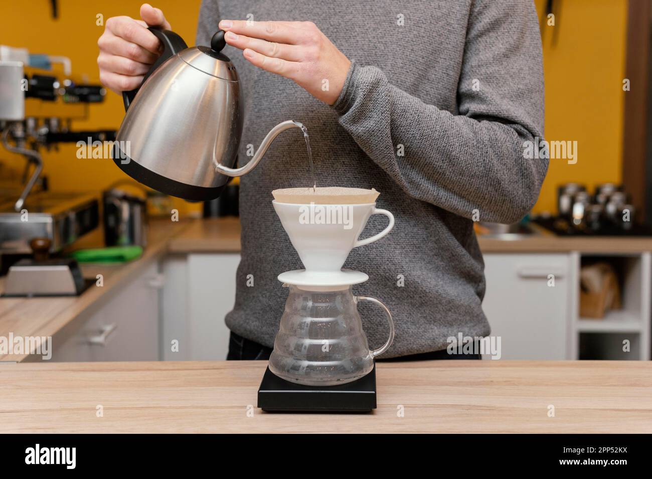 Vista frontale barista maschio che versa il filtro del caffè con acqua calda Foto Stock