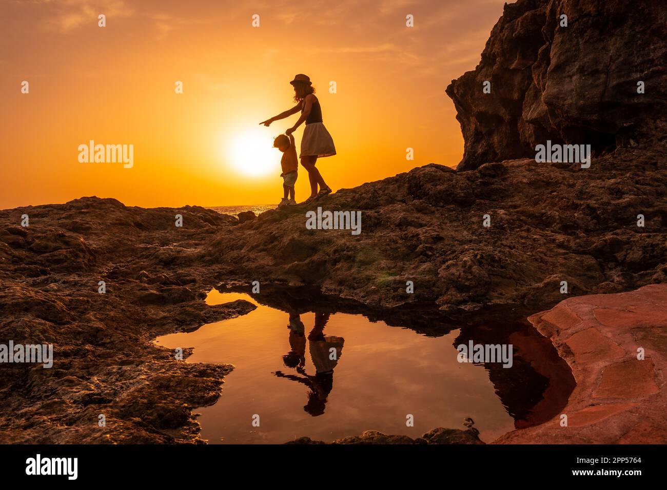 Silhouette di madre e figlio a piedi al tramonto sulla spiaggia di Tacoron a El Hierro, Isole Canarie, concetto di vacanza, tramonto arancione, a piedi Foto Stock