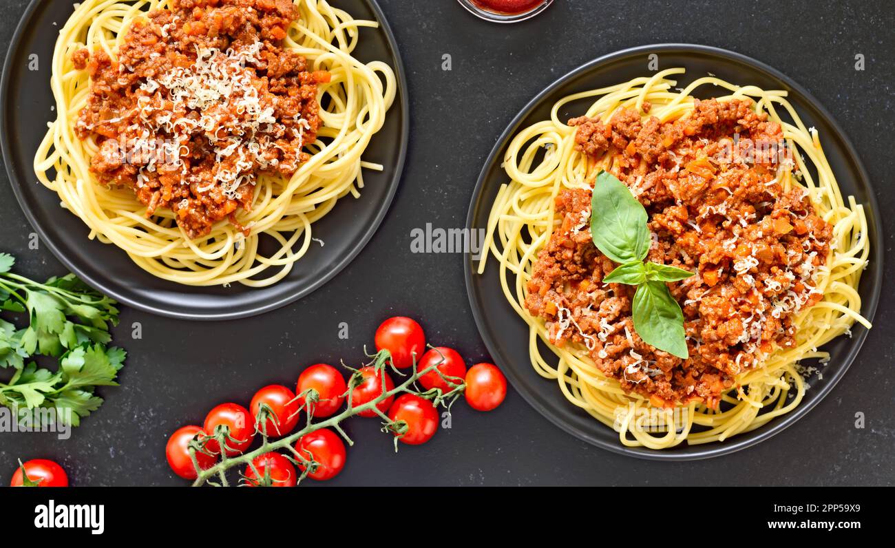 Spaghetti bolognesi su piatto su fondo di pietra nera. Vista dall'alto, disposizione piatta Foto Stock
