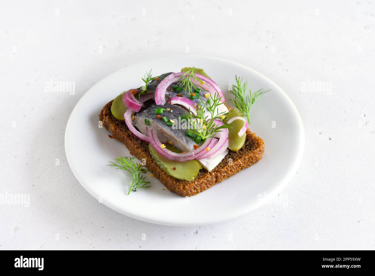 Sandwich con pesce di aringa e cetrioli di sottaceti su piatto bianco Foto Stock