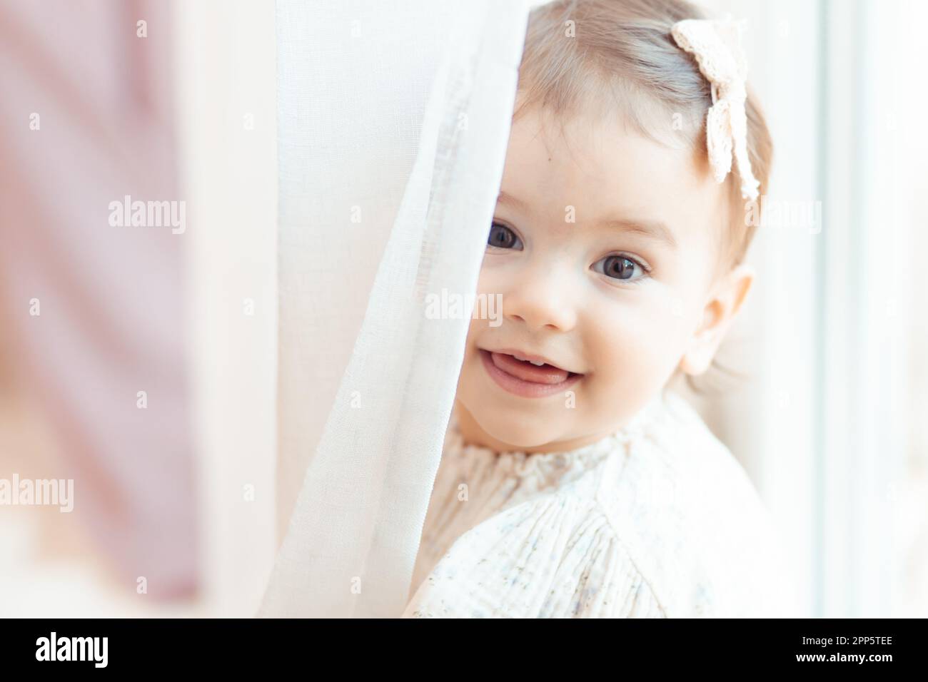 Primo piano ritratto di una bambina di un anno che guarda dietro il sipario Foto Stock