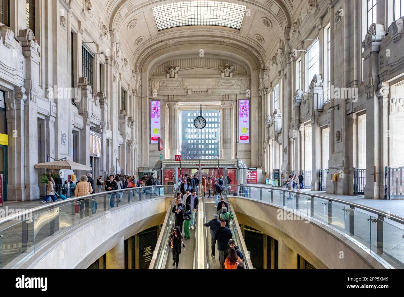 Persone su scala mobile all'interno del magnifico interno della sala d'ingresso al piano terra della stazione ferroviaria di Milano Centrale Foto Stock