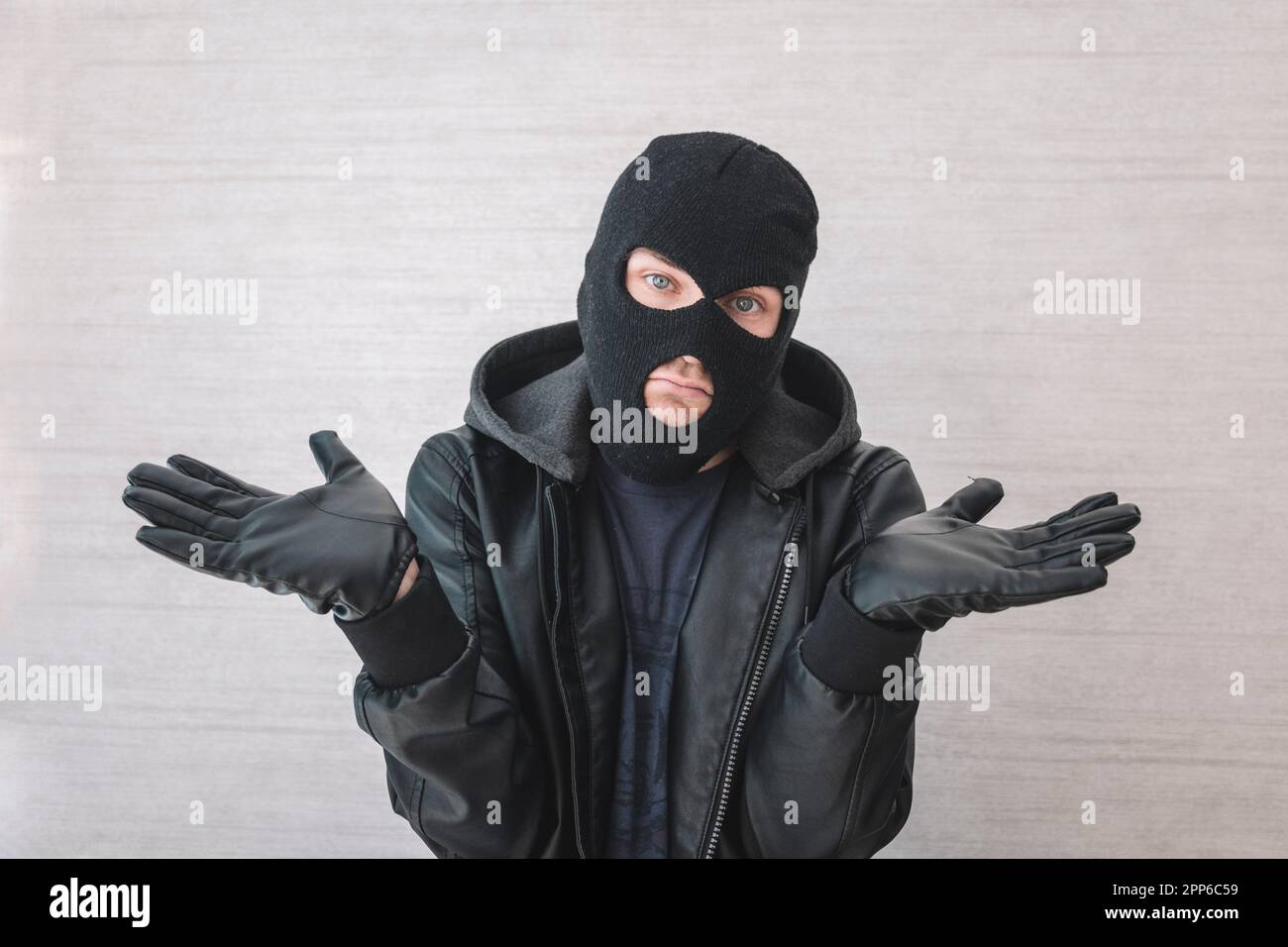 Giovane bell'uomo che indossa una maschera di scassinatore senza indizi e confuso con le braccia aperte, nessun concetto di idea. Il ladro si scusa. giustificazione dell'arresto Foto Stock