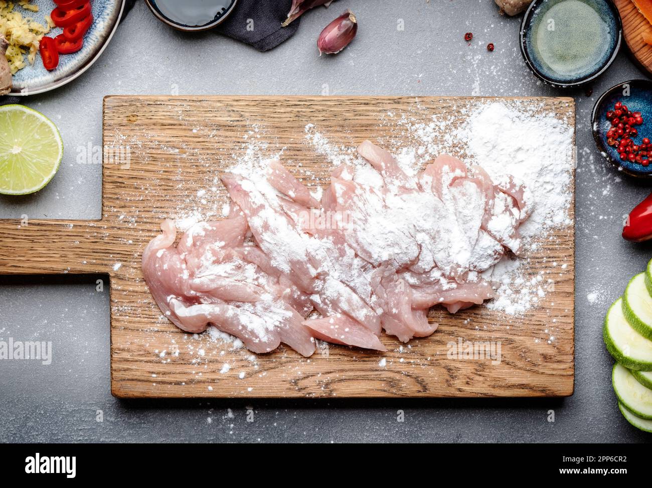 Cibo sfondo. Pollo a fette cosparso di amido sul tagliere., verdure, zenzero, lime, peperoncino, aglio, salsa di soia e aceto di riso Foto Stock