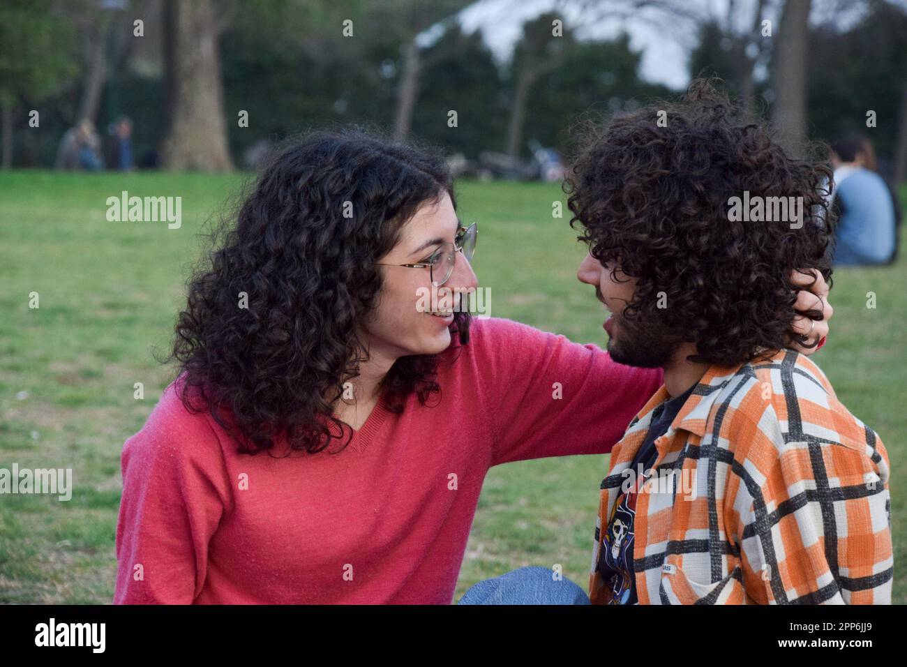 Una coppia romantica si sedette al parco parlando e carezzandosi Foto Stock