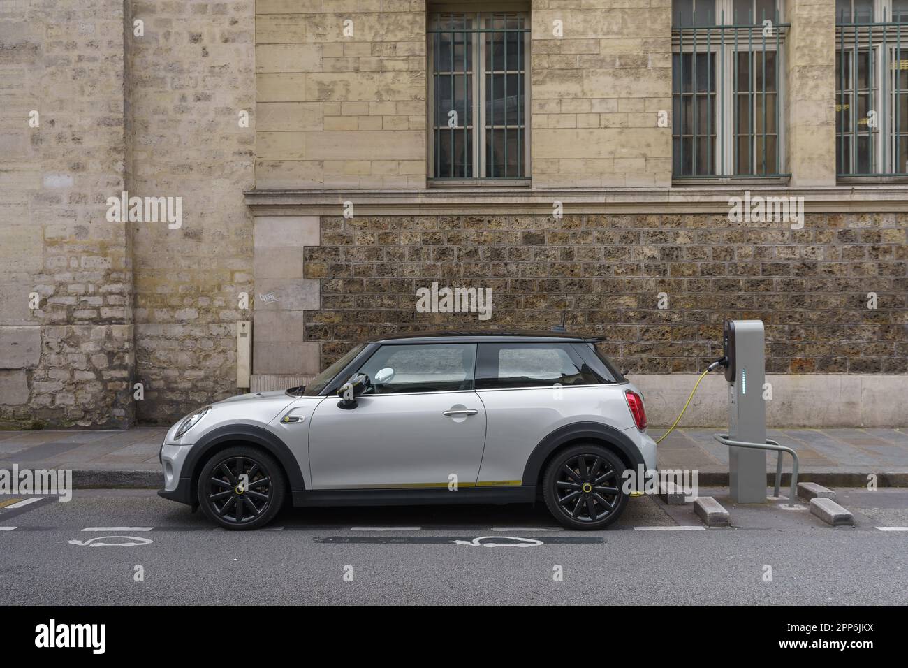 Auto elettrica bianca presso una stazione di ricarica sulla strada. Parigi, Francia. Foto Stock