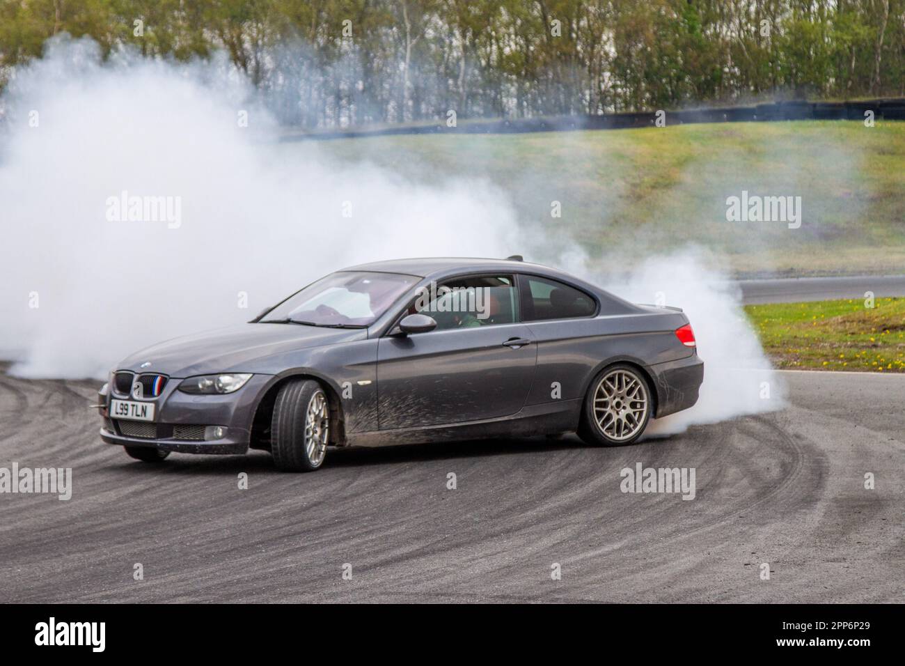 BMW 335I se Grey Car Coupe benzina 2979 cc, gomma bruciante e pneumatici che urlano a tre 3 Sisters Race Circuit a Wigan, Lancashire UK Foto Stock