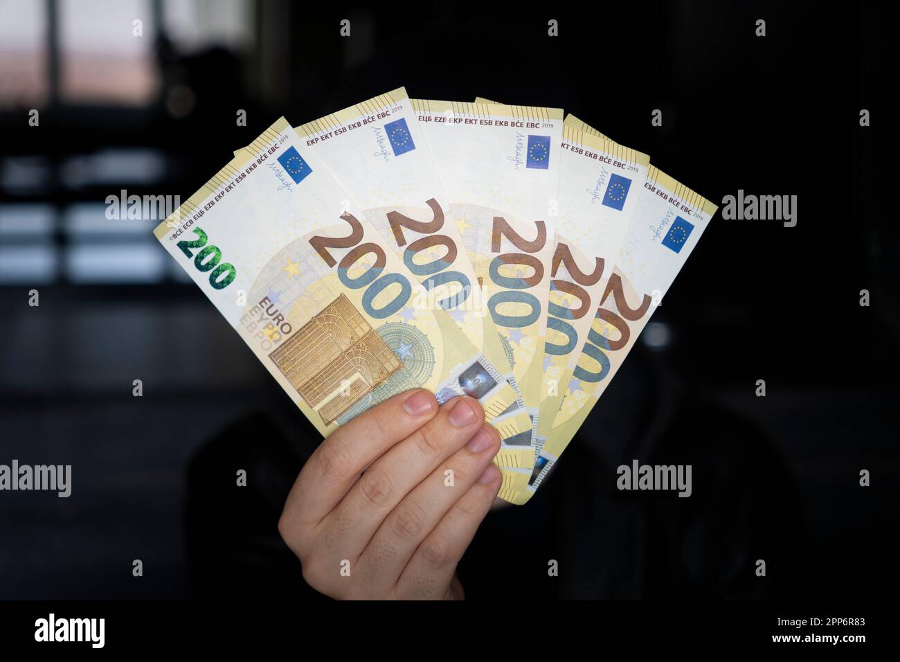 la mano dell'uomo tiene l'euro, li considera e paga. Carta moneta euro nelle mani. 1000 euro in contanti su sfondo scuro. Concetti di investimento e pr Foto Stock