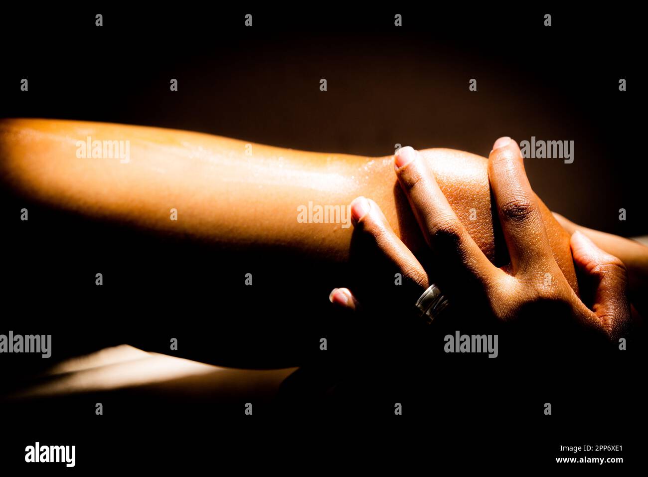 Una donna applica lozione alla gamba. Mentre massaggia delicatamente la lozione nella sua pelle, sente una sensazione lenitiva. Foto Stock