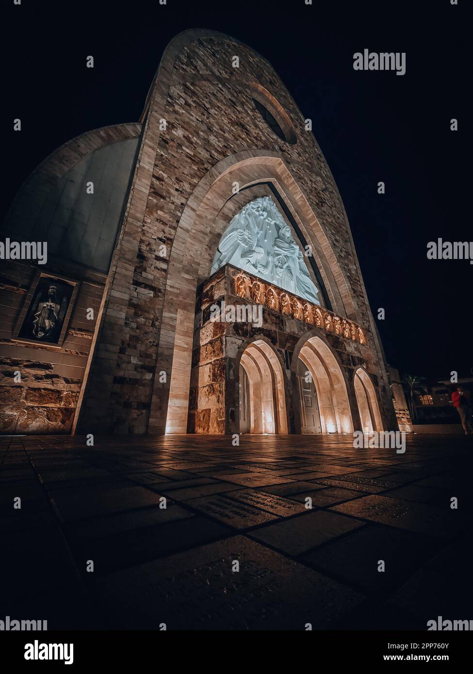 Una chiesa tradizionale in pietra si erge sullo sfondo di un cielo notturno scuro, illuminato da un'unica fonte di luce Foto Stock