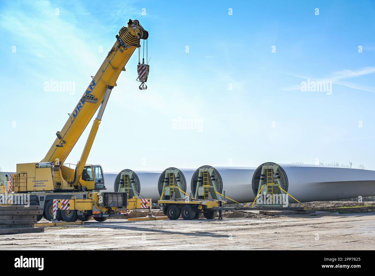 Rieps, Germania, 22 aprile 2023: Pale di turbine eoliche e una gru industriale pesante immagazzinate vicino al cantiere di una fattoria di energia eolica, installare un Foto Stock