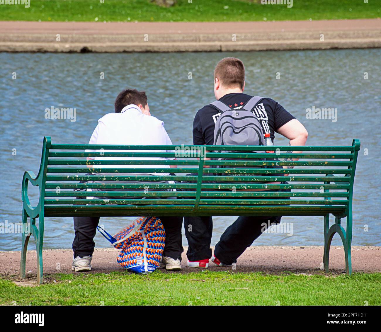 due adolescenti su una panchina vicino a uno stagno Foto Stock