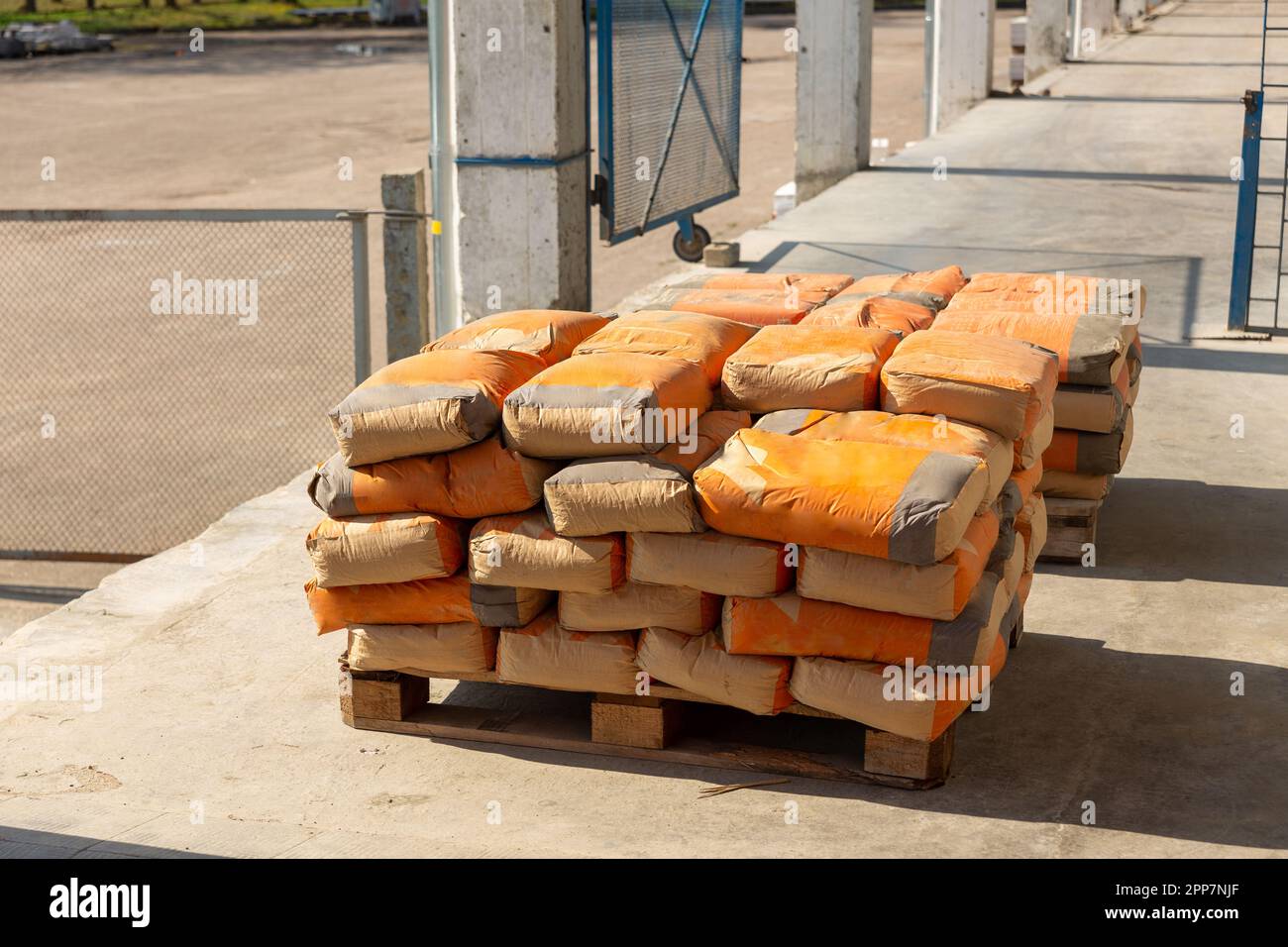 I sacchetti di cemento vengono collocati su pallet e stoccati in magazzini. Sacchi di cemento sono stati scaricati dal magazzino sulla rampa e preparati per la spedizione a. Foto Stock