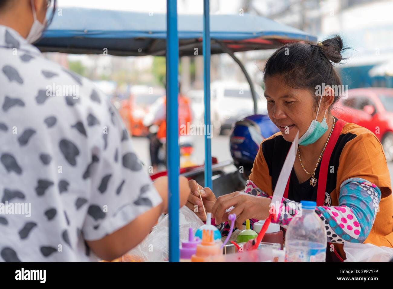 Pattaya, Thailandia - Marzo 14,2023:South Pattaya Road una donna tailandese più anziana stava vendendo cibo di strada a buon mercato ad un uomo asiatico. Foto Stock