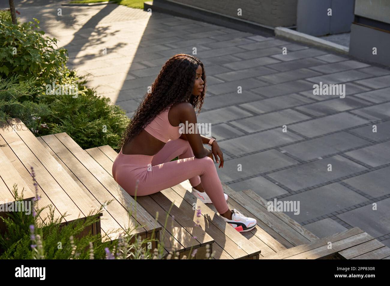 Giovane donna africana in forma modello seduto nel parco della città rilassante all'aperto. Foto Stock