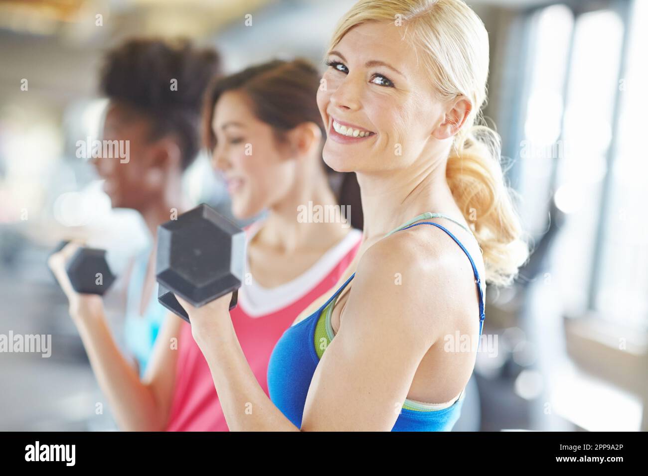 Devo candidarmi come allenatore... una bella bionda sorridente alla telecamera con due donne sullo sfondo. Foto Stock Devo candidarmi come allenatore... una bella bionda sorridente alla telecamera con due donne sullo sfondo. Foto Stock