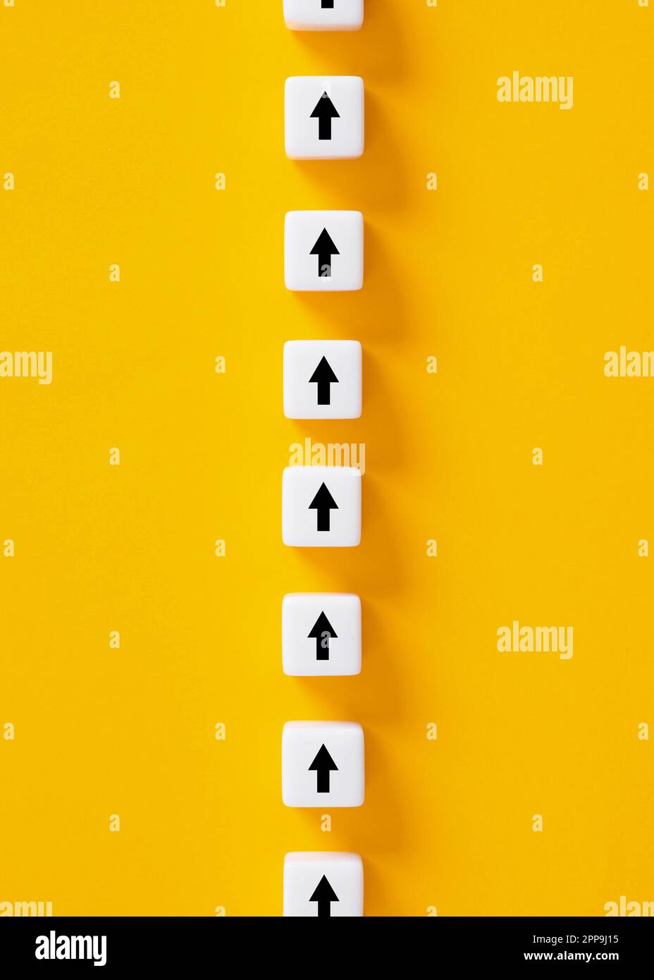 Miglioramento delle prestazioni aziendali. Seguendo una direzione o un percorso. Simboli delle frecce su cubi bianchi su sfondo giallo. Foto Stock
