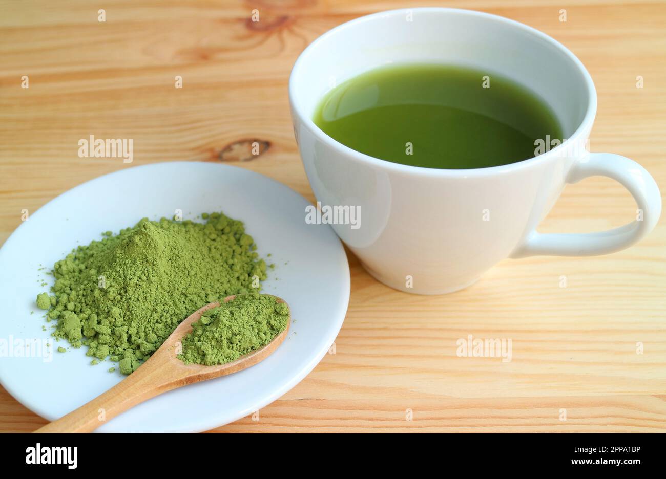 Tazza di tè verde Matcha caldo con un piatto di tè Matcha in polvere su tavolo di legno Foto Stock