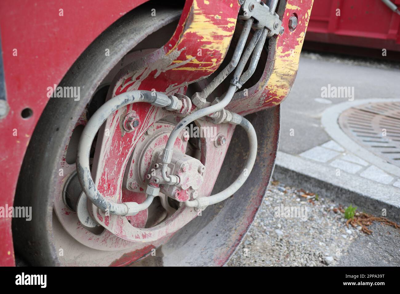 Dettaglio in primo piano di un rullo motorizzato rosso con tracce di terra e argilla dell'ultimo lavoro sul campo. Foto Stock