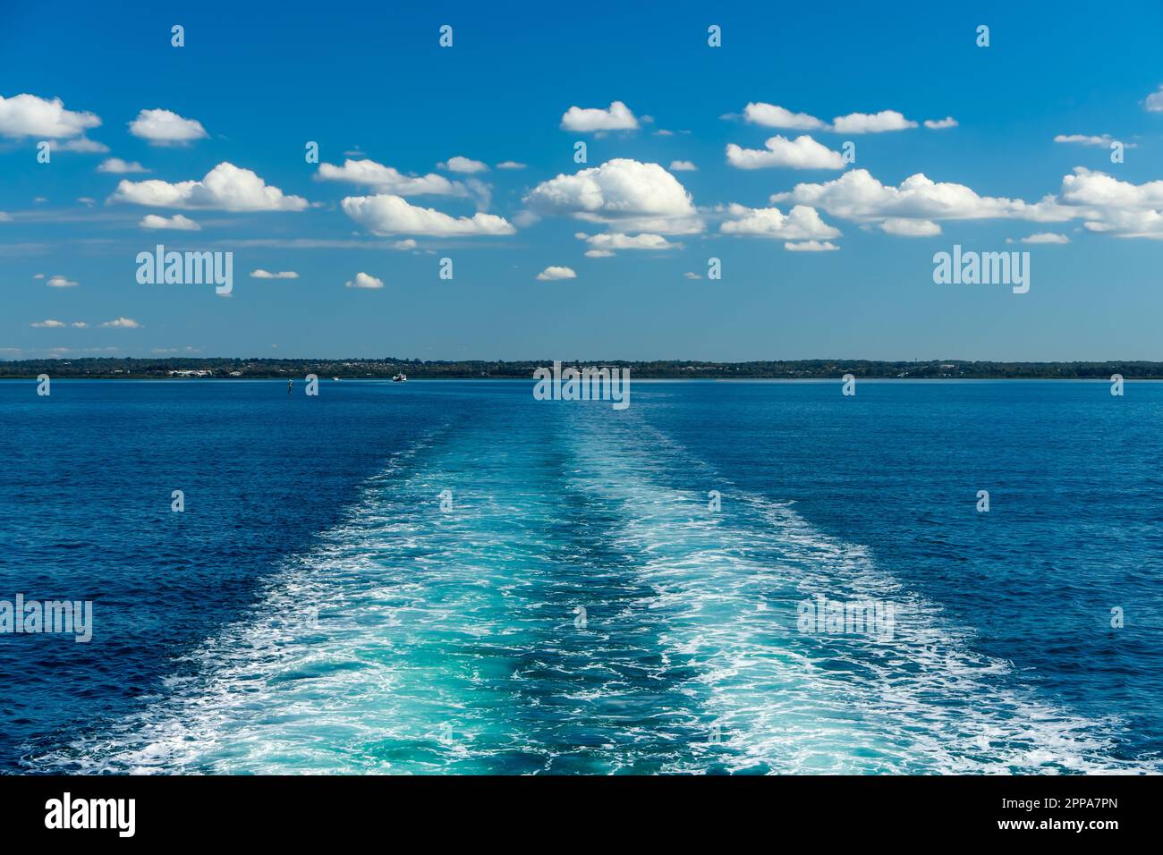 Acqua turbolenta sulla scia di un traghetto, sotto le soffici nuvole bianche che galleggiano nel cielo blu. Moreton Bay, Queensland, Australia Foto Stock